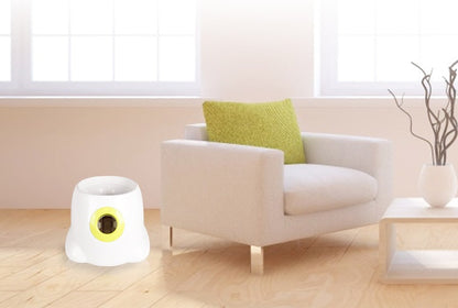White electronic device with a yellow light on a wooden floor in a living room.