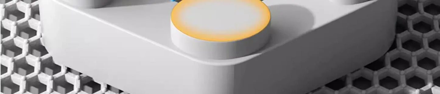 Close-up of a white electronic device with a yellow button on a honeycomb background