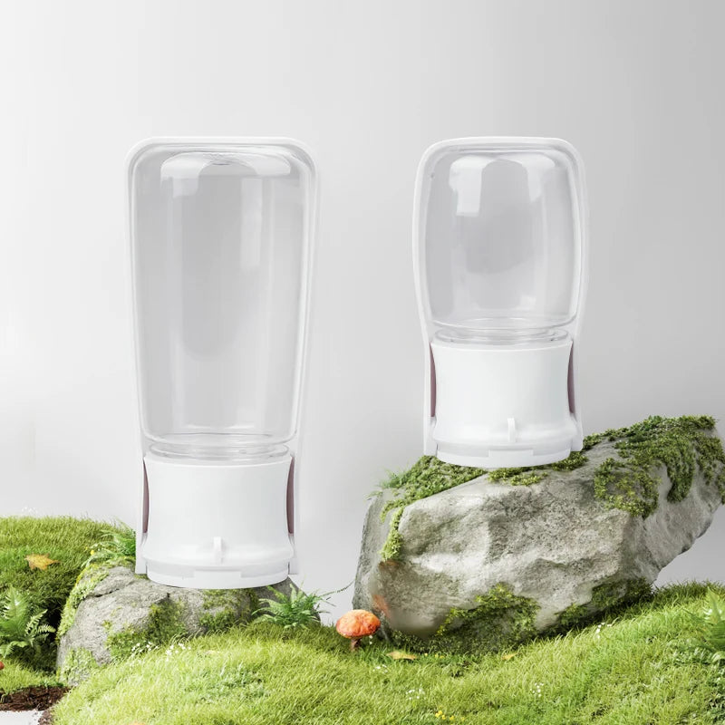 Two clear glass tumblers on a rock with grass and flowers in the background