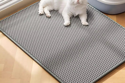 Cat lying on a gray mat with a honeycomb pattern on a wooden floor.