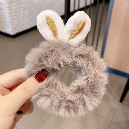 Fluffy gray scrunchie with bunny ears held by a hand.