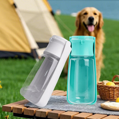 Two water bottles on a picnic table with a dog in the background at a campsite.