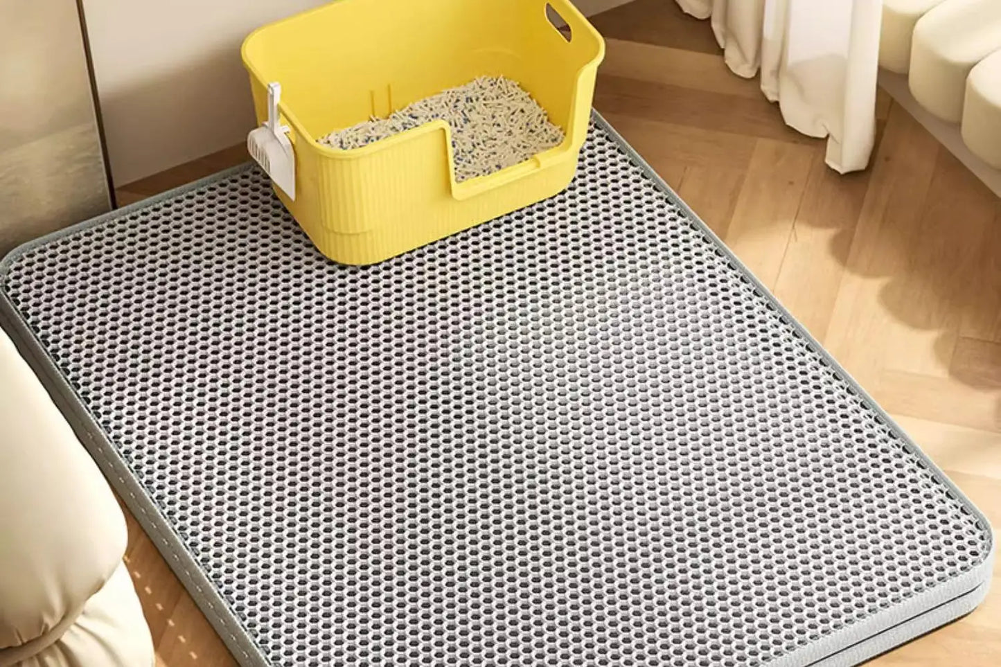Gray perforated mat with a yellow litter box on a wooden floor.